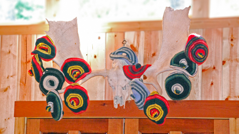 colorful hats hanging on a set of antlers.