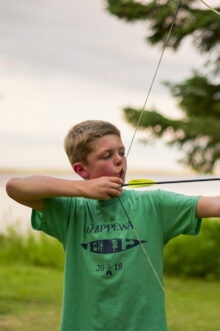 boy pulling back a bow with an arrow.