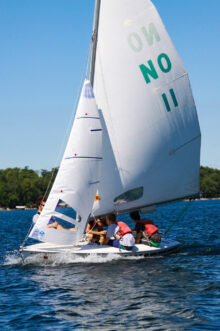 boys sailing a small boat on a lake.