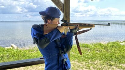 boy standing with rifle next to cass lake in minnesota.