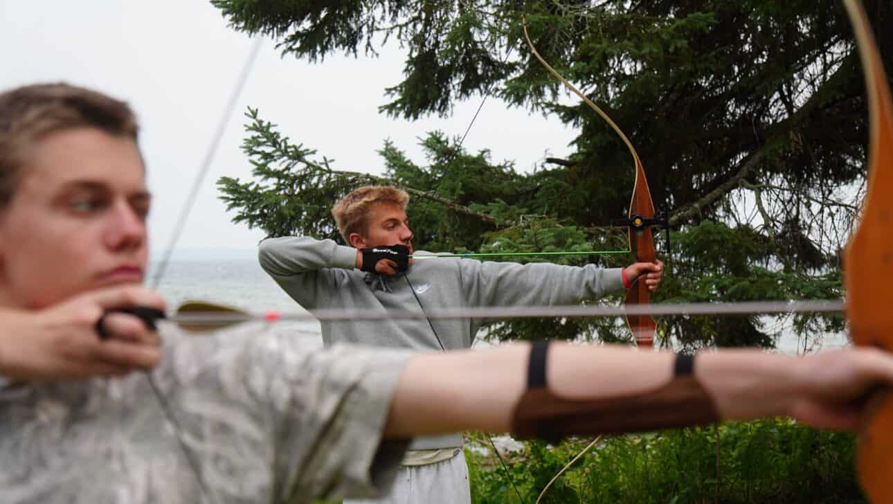 two boys shooting archery at summer camp.