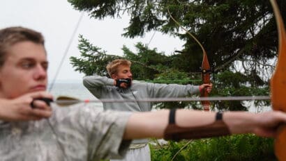 two boys shooting archery at summer camp.