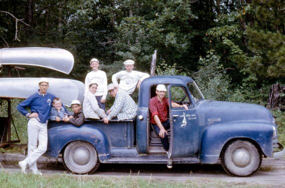 boys sitting in the back of an old blue pickup truck.