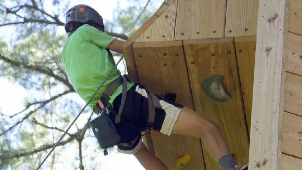 boy climbing outside on a climbing wall.