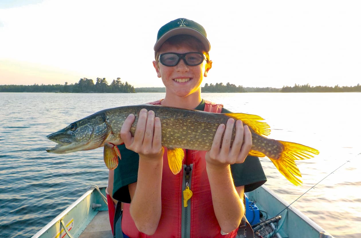 boy holding fish and smiling.
