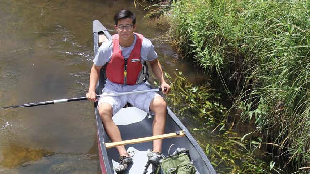 boy on a canoe in a marsh.