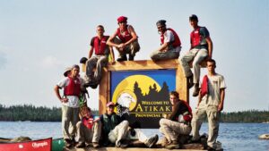 boys on welcome to atikaki sign on lake.