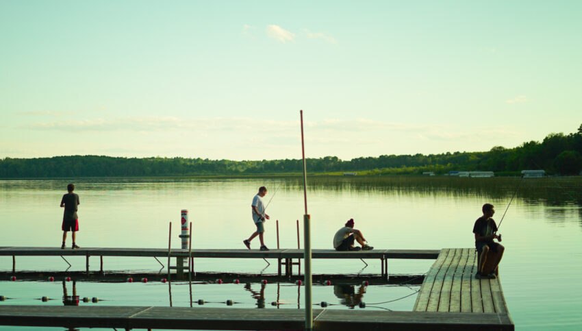 boys on a dock on a lake.