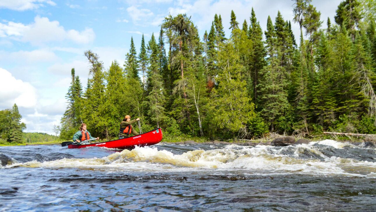 canoe going through whitewater rapids.