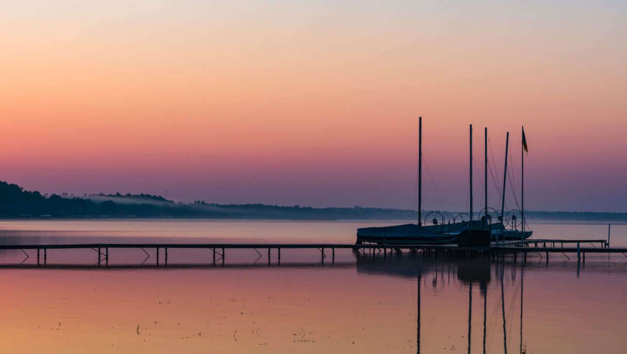 rainbow colored sunrise over boat dock.