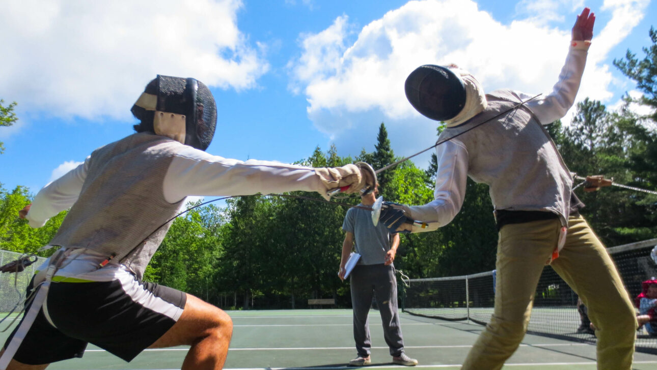 two boys fencing outdoors.