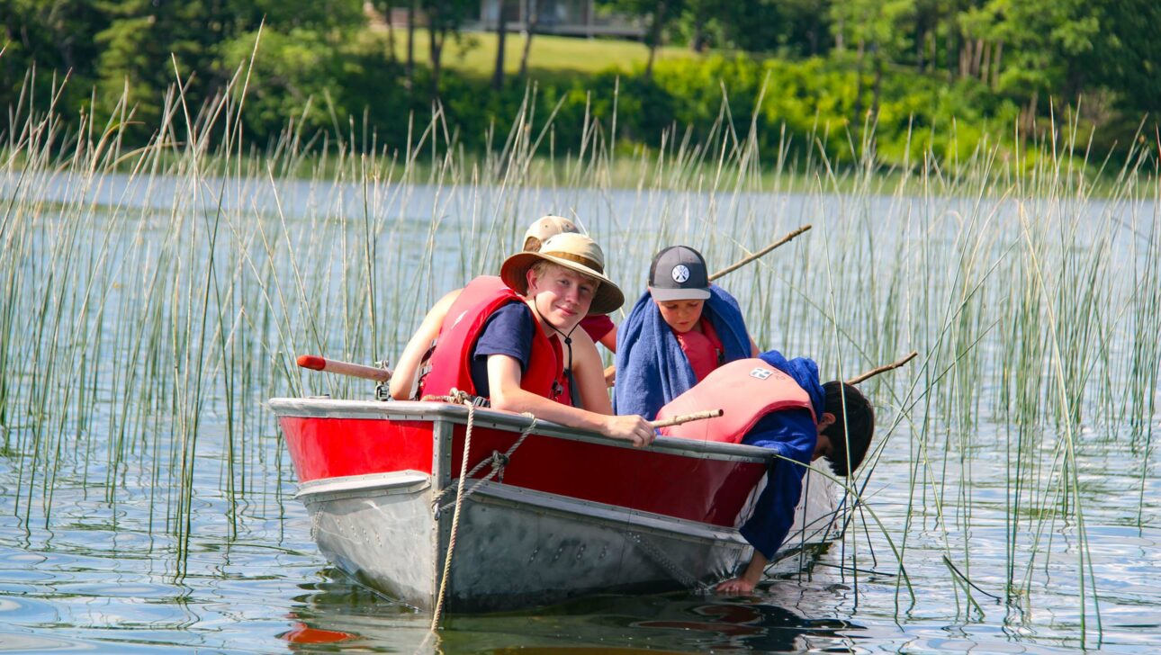 boys fishing on a rowboat in a light marsh.