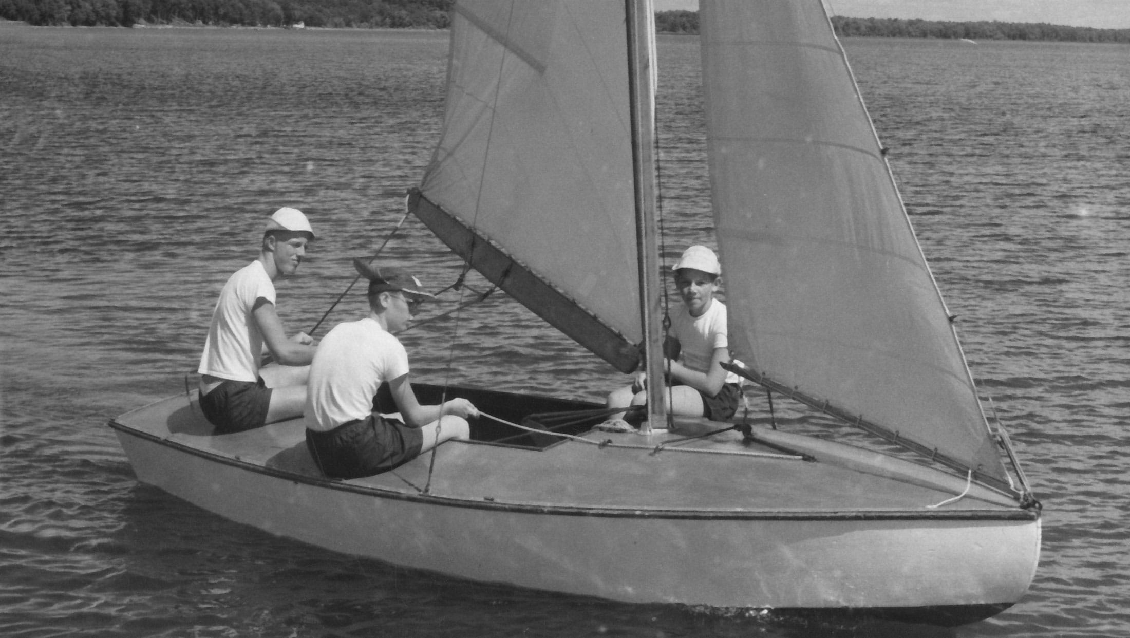 black and white photo of boys on sailboat.