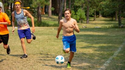 shirtless boy dribbling soccer ball.