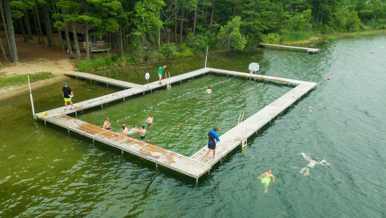 boys swimming next to dock.