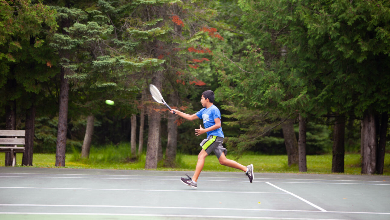 boy returning tennis shot.