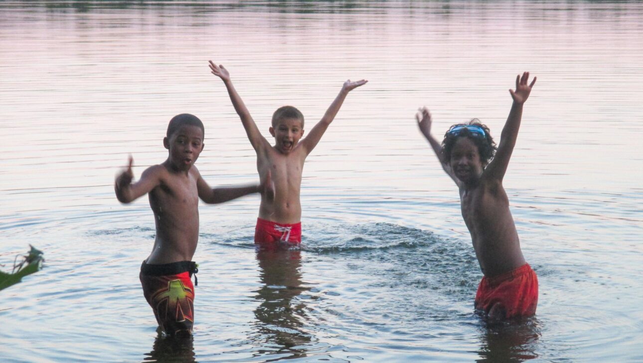 Three young boys swimming.