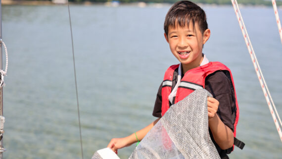boy holding a sail on a boat.
