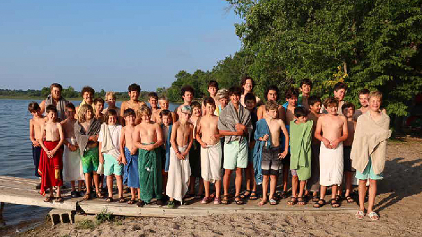 group of boys in swimsuits and towels on a beach after a swim.