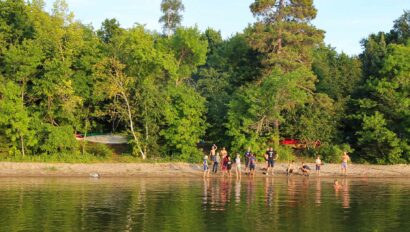 campers waving from an island across the water.