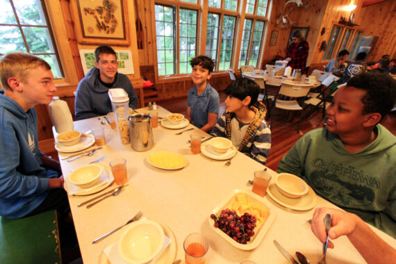 Campers sitting around a table at mealtime.