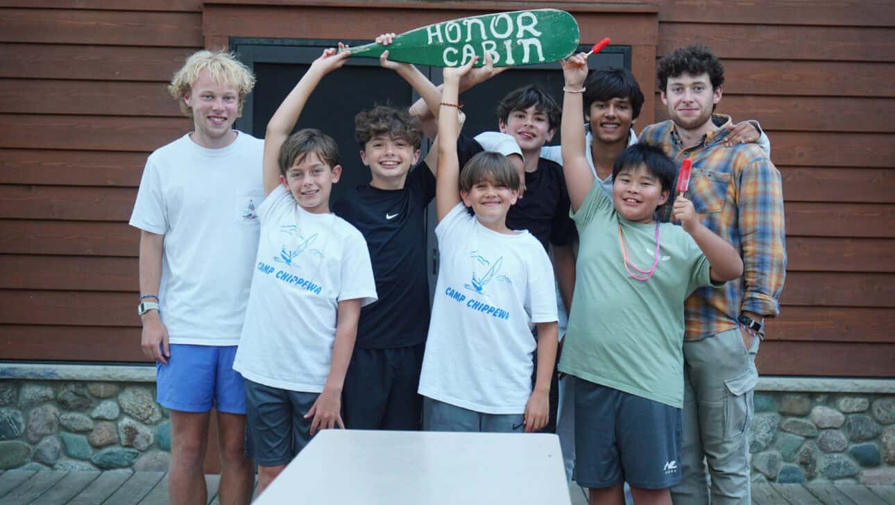 group of campers and two counselors holding up honor cabin sign and smiling.