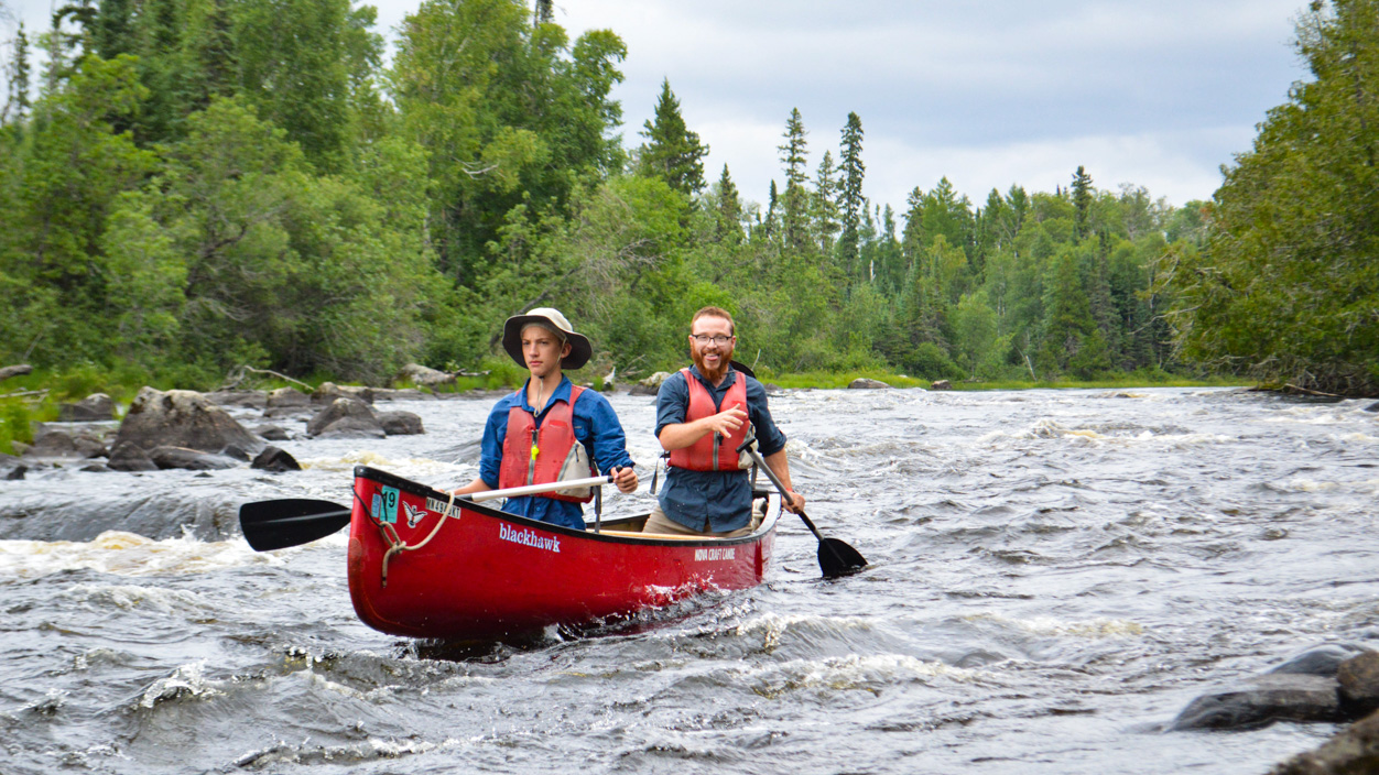 boy and a camp counselor canoeing down a river.