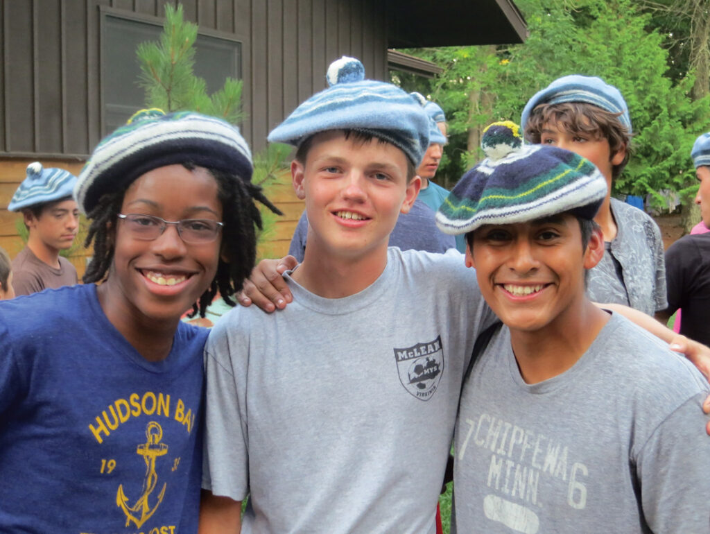 Three friends wearing hats and smiling.