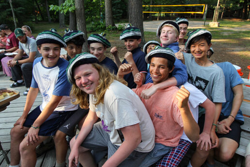 group of boys in hats laughing and handing on each other.