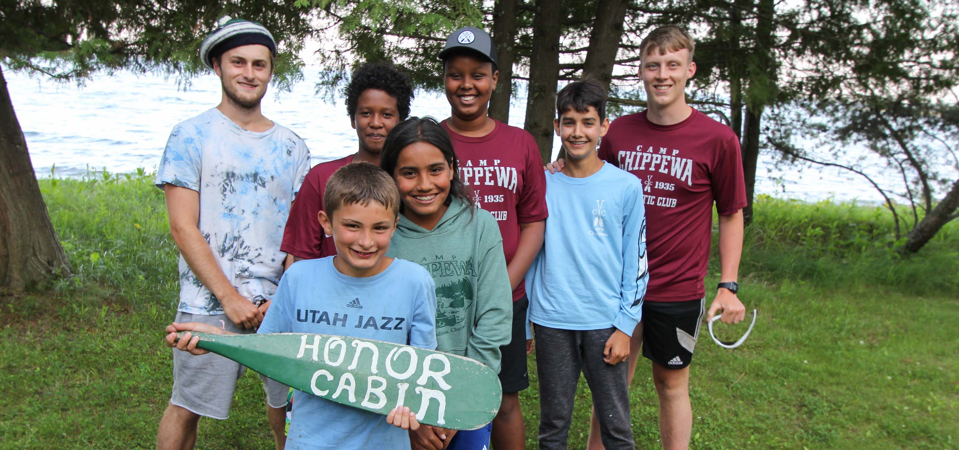 group of boys smiling with one holding a paddle that says honor cabin.