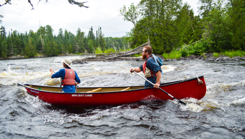 two boys on a canoe on rapids.