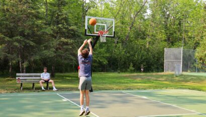 boy shooting hoops on basketball court.