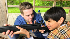teen showing boy how to shoot rifle close up.
