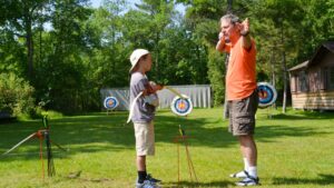 man showing boy how to shoot bow.