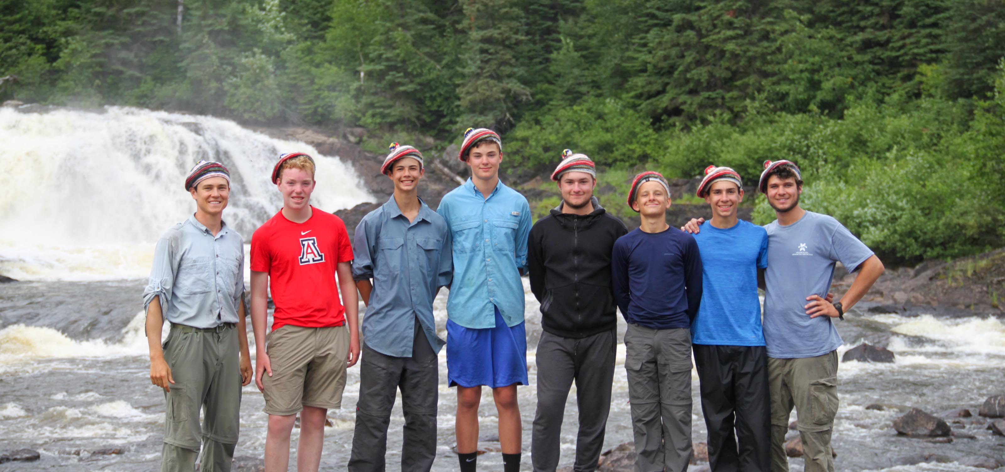group of boys standing in front of a waterfall smiling for the camera.