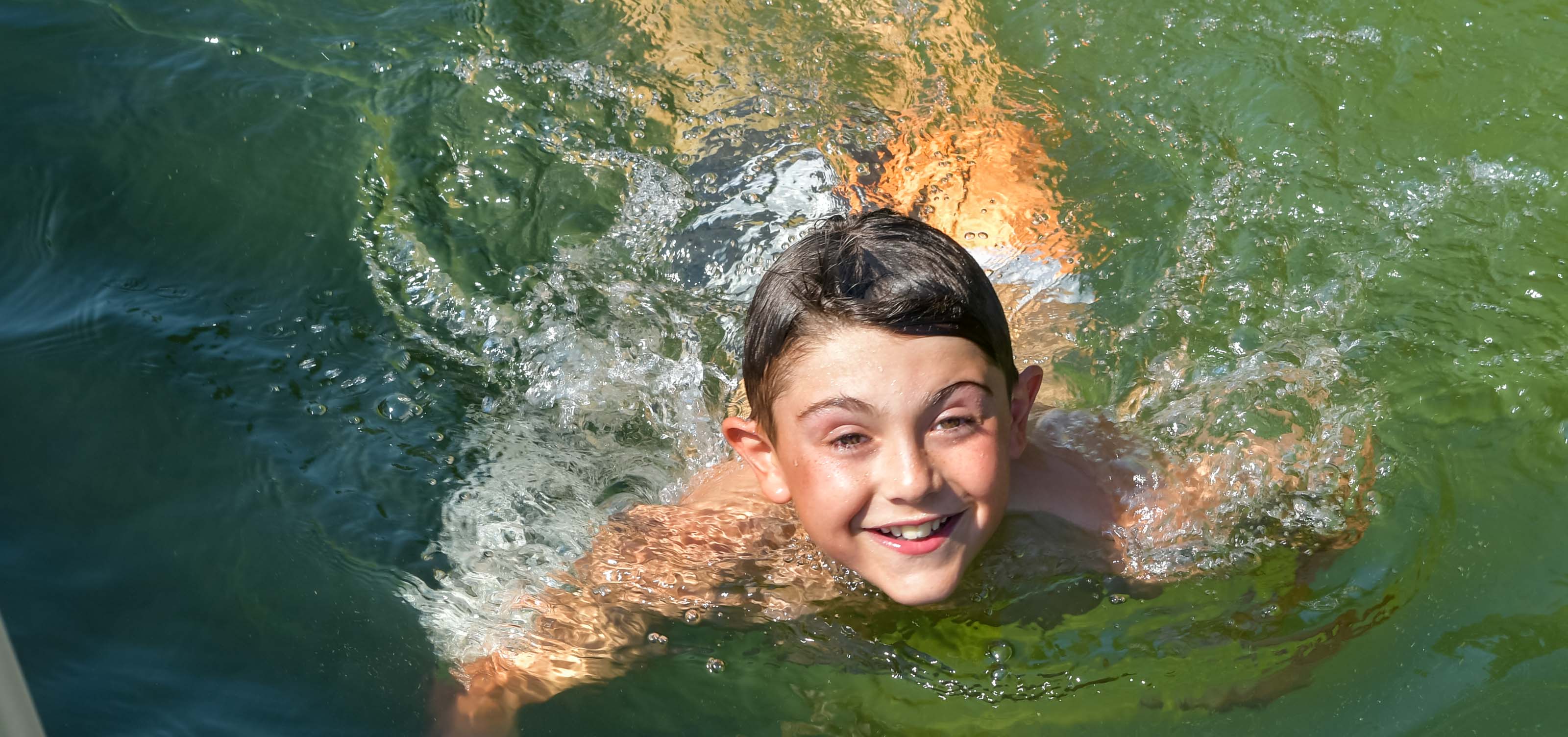 boy swimming and smiling.