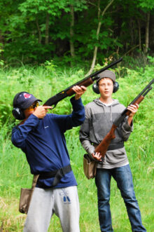 boy aiming a long gun while trap shooting.
