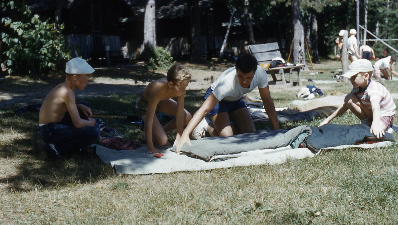 Vintage image of campers from the 1980s packing their sleeping bag.