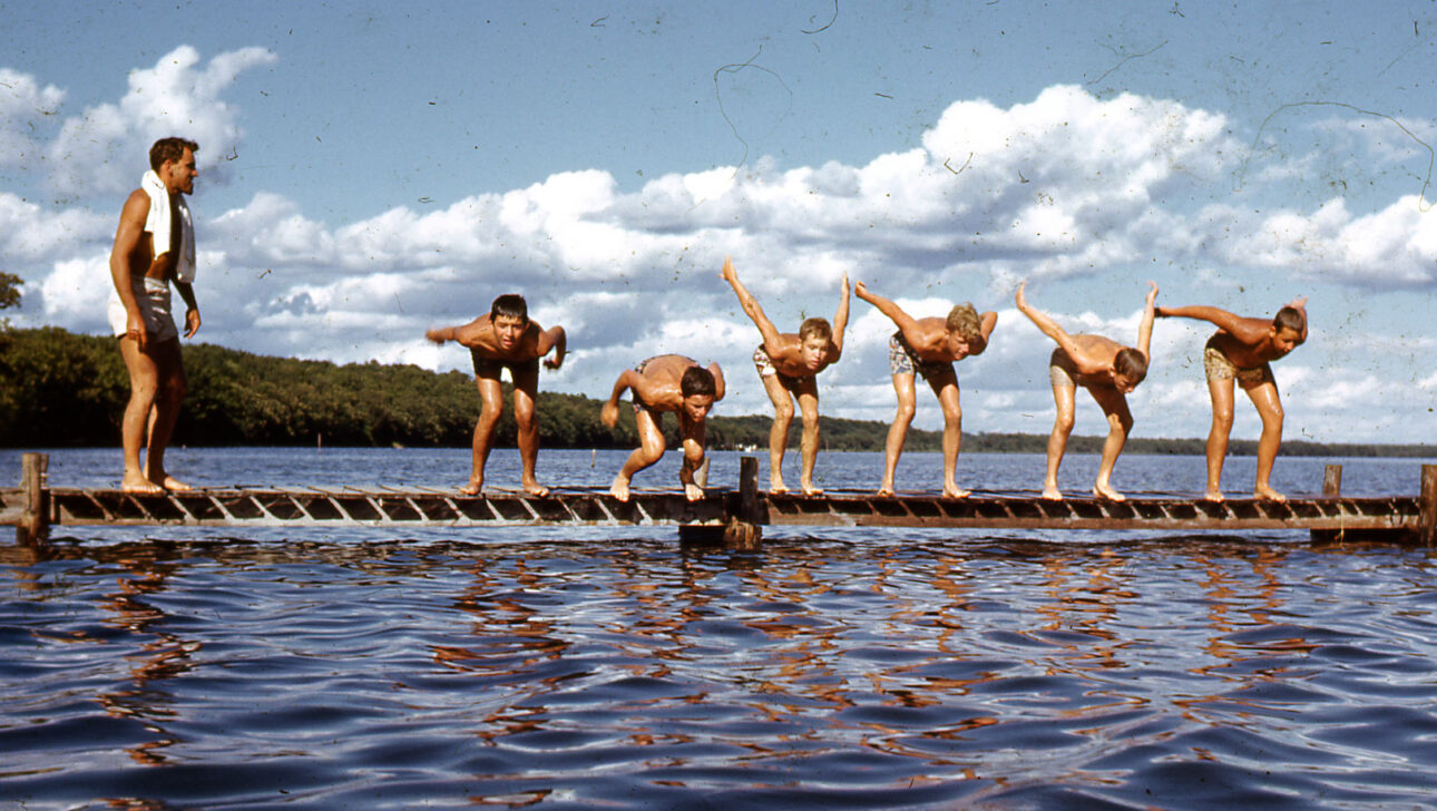 Vintage image of campers about to dive in to a lake.