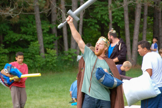teen male larper yelling while holding sword in the air.