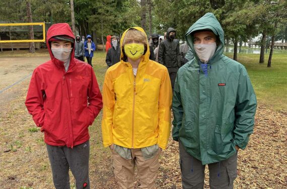 three boys wearing rain jackets and masks.