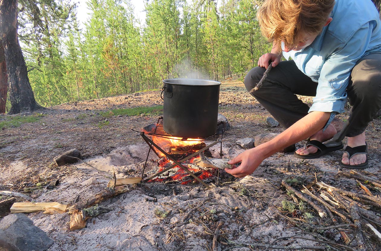 camper building and tending a campfire outside.