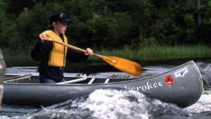 canoeist paddling through rapids in the 1980s
