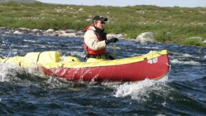 canoeist paddling through rapids.