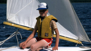 boy sitting on the deck of a sailboat.
