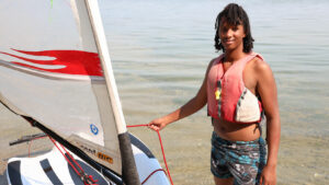 boy standing by a sailboat.