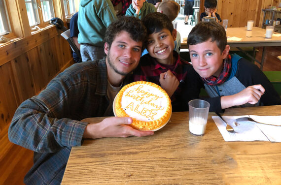 counselor and two campers smiling with a birthday cake.