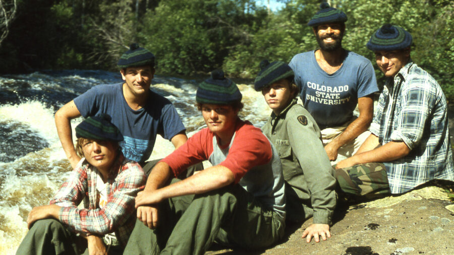 a group wearing tams sitting by rapids.