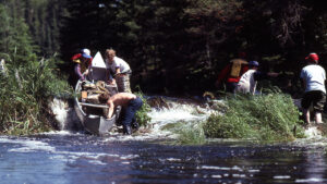 group lowering a canoe down rapids.