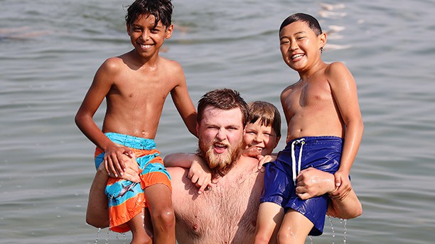 counselor holding campers up on his shoulders in lake